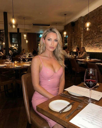 Woman wearing Luna Midi Dress in soft pink at a restaurant with wine, showcasing elegant party style by Lauven.