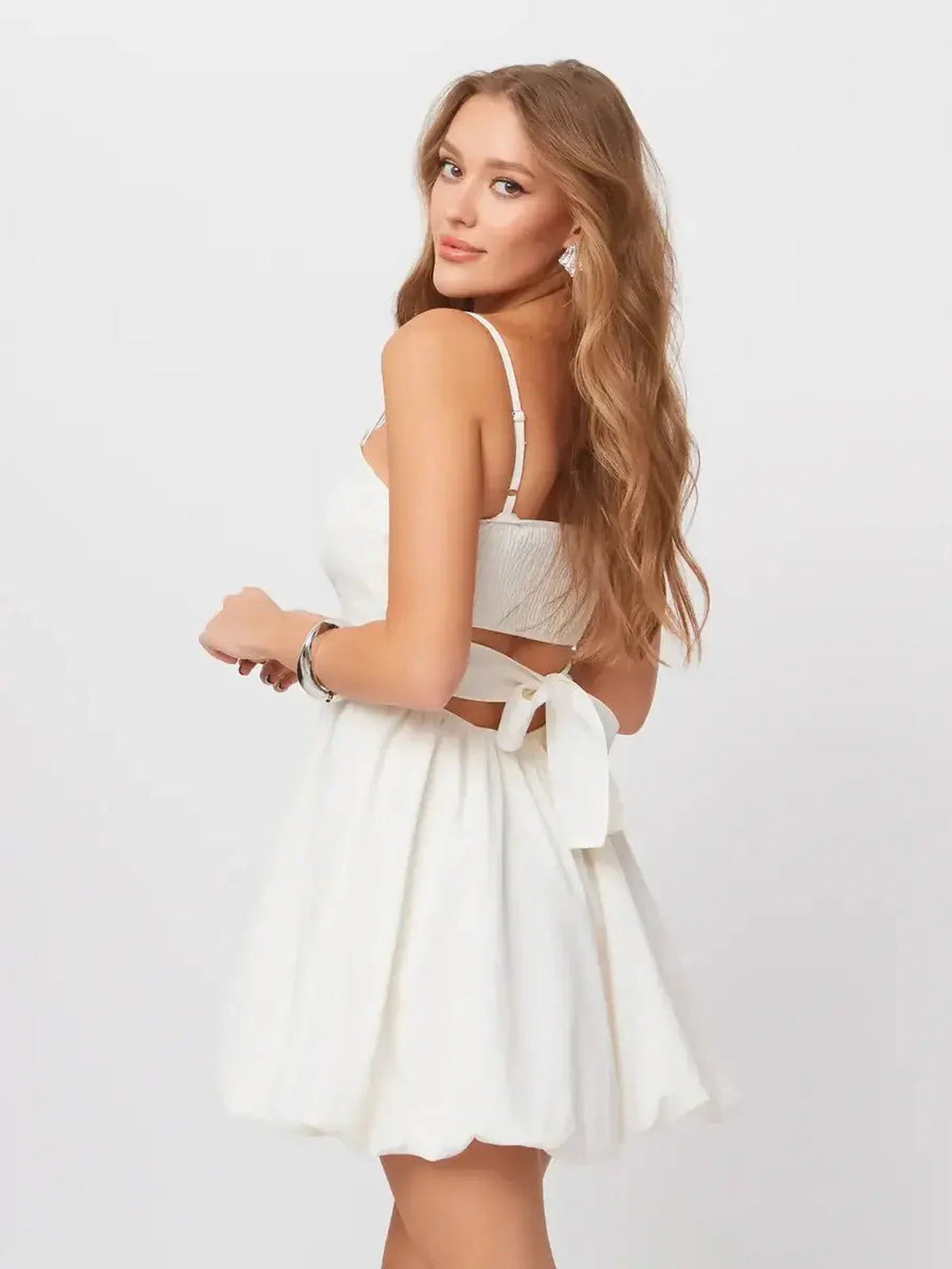 Model wearing a white Luna Mini Dress featuring adjustable spaghetti straps and a bow detail at the back.