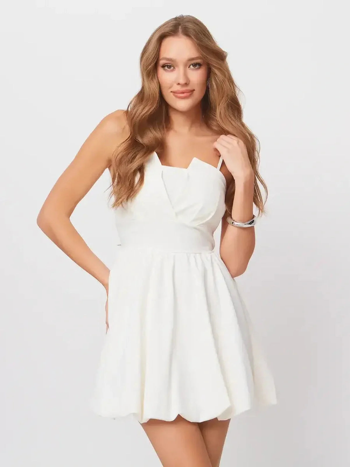 Stylish woman in a white Luna Mini Dress with adjustable straps and back bow, perfect for summer parties.