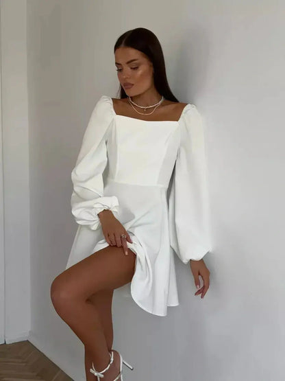 Model showcasing the Luna Whisper white mini dress with long voluminous sleeves and square neckline.