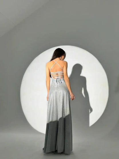 Back view of a model in a sparkling silver Lunar Halo Maxi Dress with delicate straps and side slit.