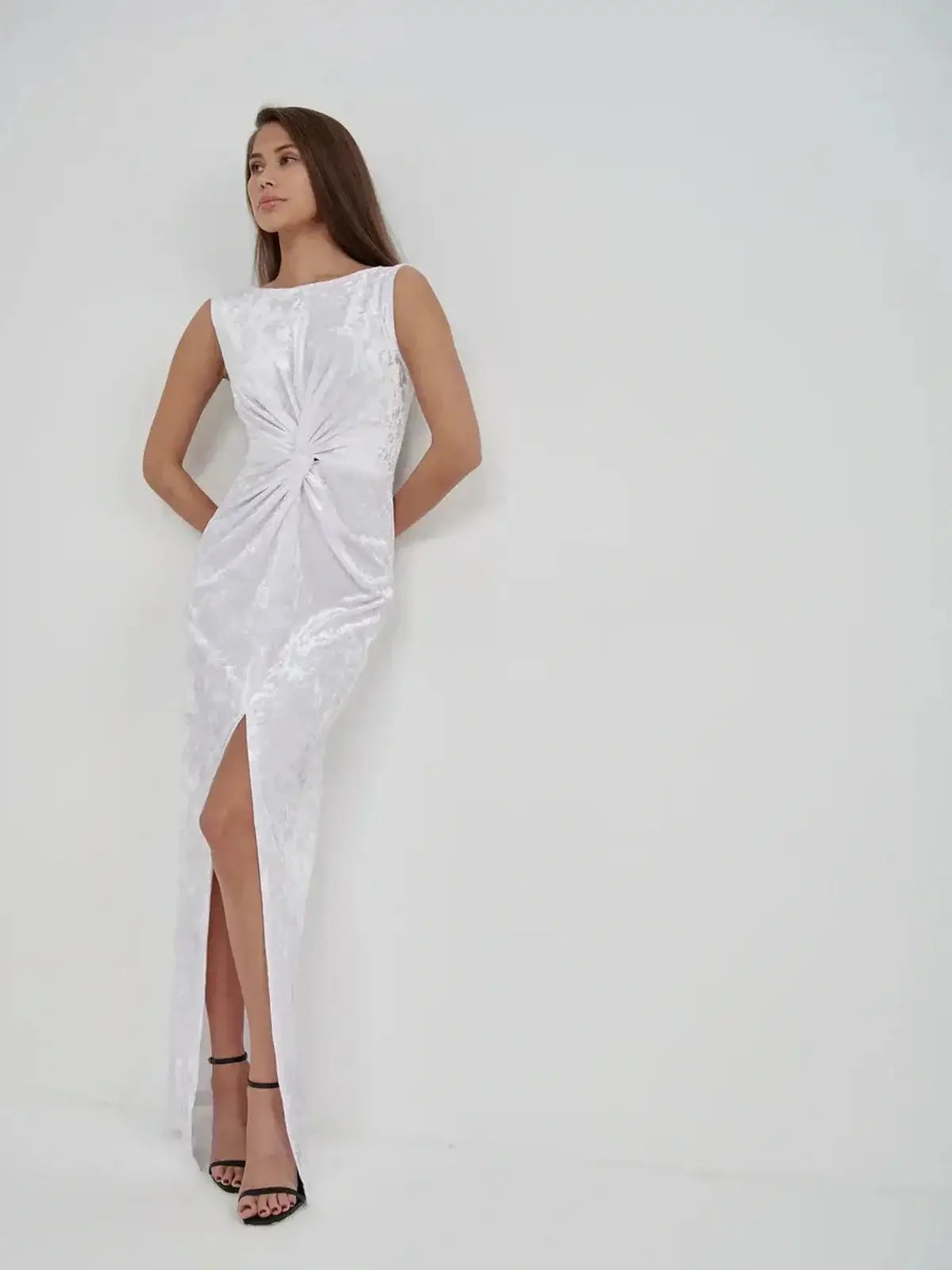 Woman in Lustre Twist Maxi Dress, a white crushed velvet gown with architectural twist detail and stylish slit.