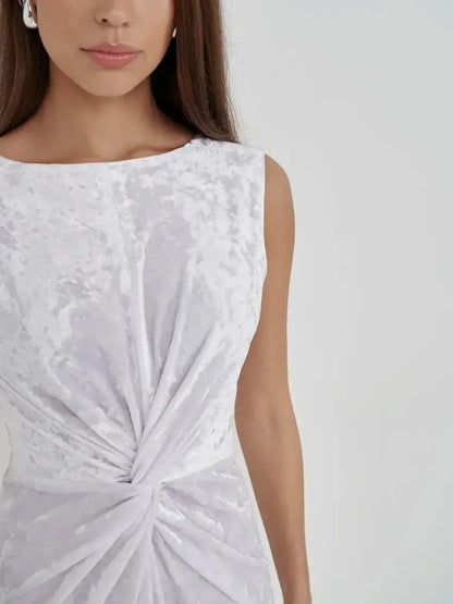 Model showcasing the Lustre Twist Maxi Dress in white crushed velvet highlighting its elegant twist and architectural design.