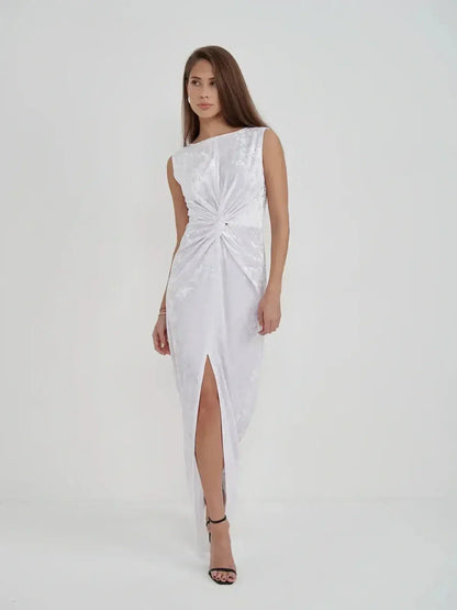 Model wearing Lustre Twist Maxi Dress, a white crushed velvet gown with slits, showcasing modern elegance and draped design.