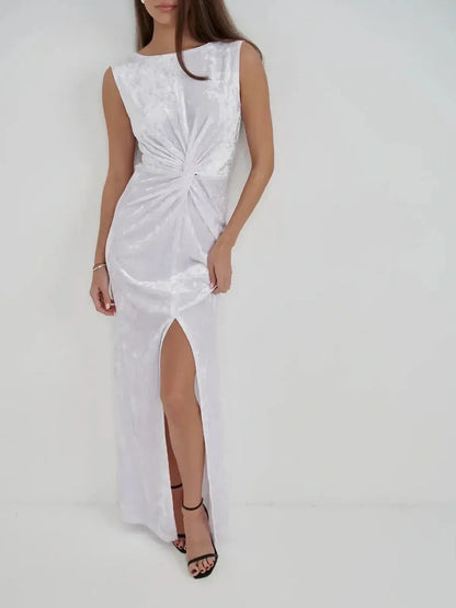 Elegant woman in Lustre Twist Maxi Dress, featuring white crushed velvet, draped design, and thigh-high slit.