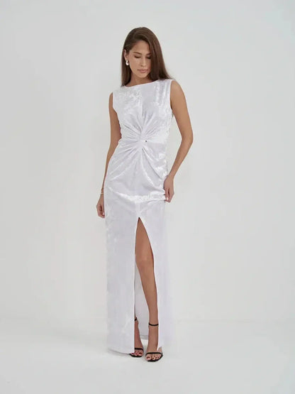Model showcasing the Lustre Twist Maxi Dress, featuring draped white velvet and a chic slit for elegant evening wear.