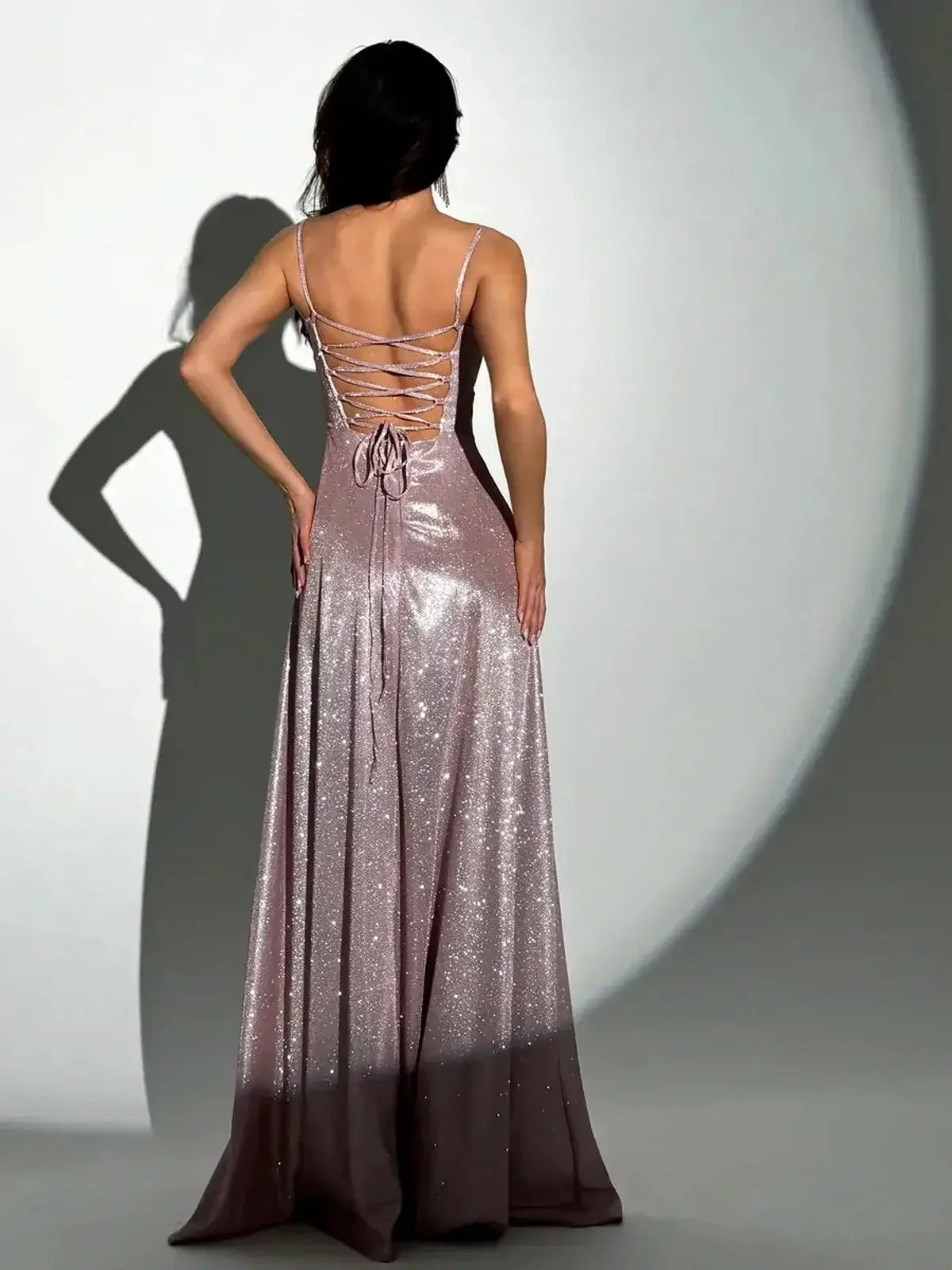 Back view of Lustrous Spell Maxi Dress in blush-pink lurex showcasing adjustable lace-up design and flowing silhouette.