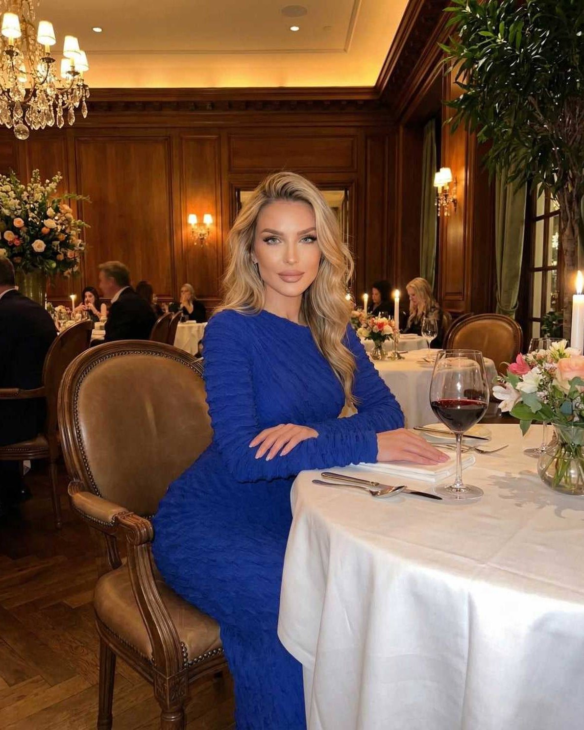 Model wearing the Marina Maxi Dress by Lauven, a sleek royal blue long sleeve knitted dress in a sophisticated dining setting.