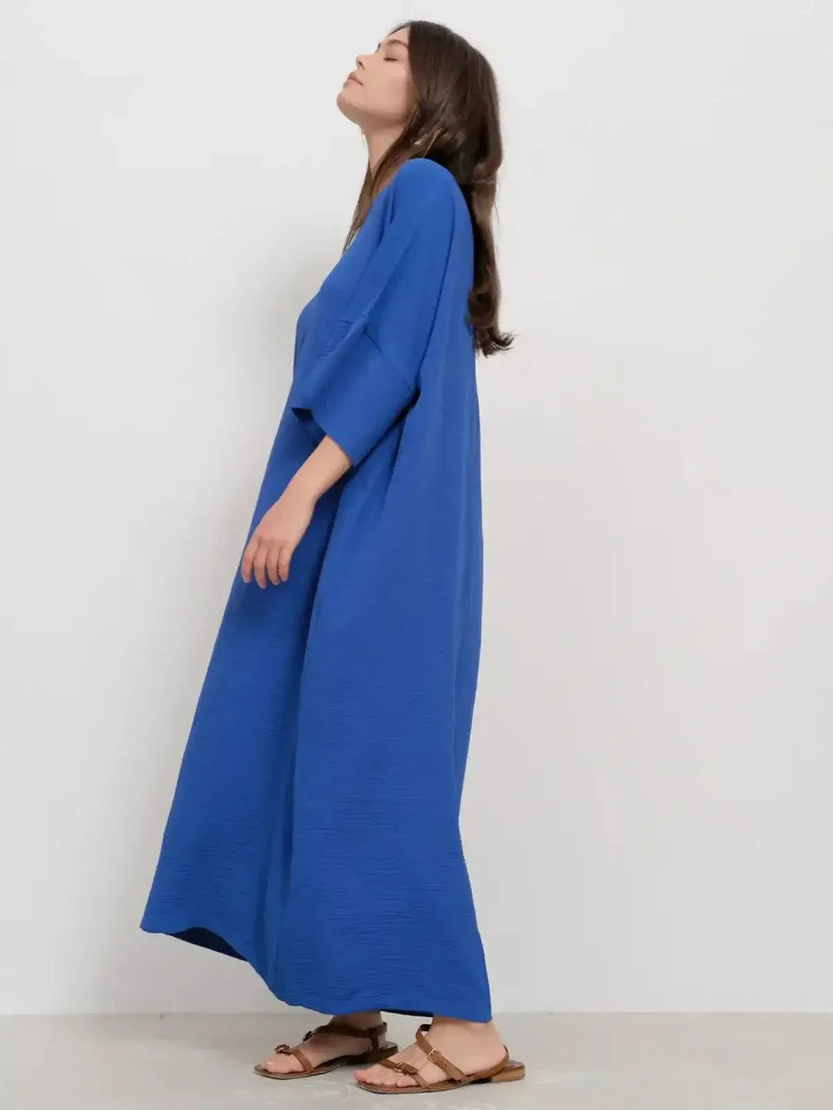 Model showcasing the Maxi Dress Azure Flow in vibrant blue, featuring a relaxed silhouette and deep V-neckline.