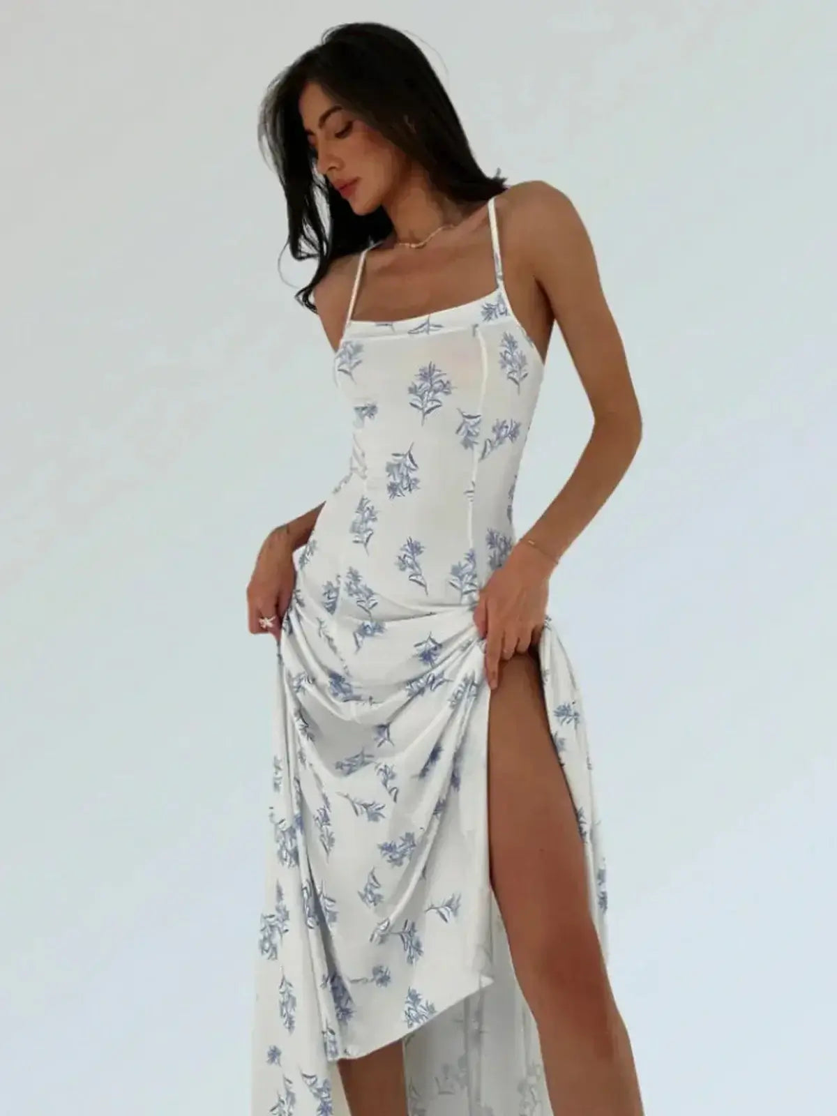 Elegant woman wearing a blue floral maxi dress with a handkerchief hem and open-back design, showcasing summer style.