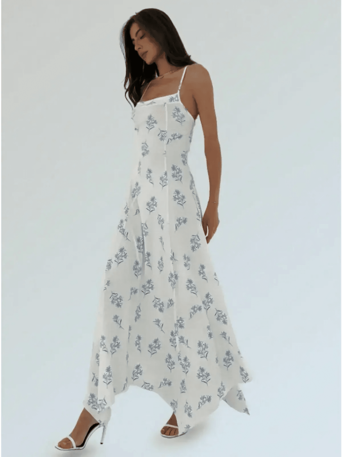 Maxi Dress Bluebelle in white with blue floral print, featuring a handkerchief hem and strappy open-back silhouette.