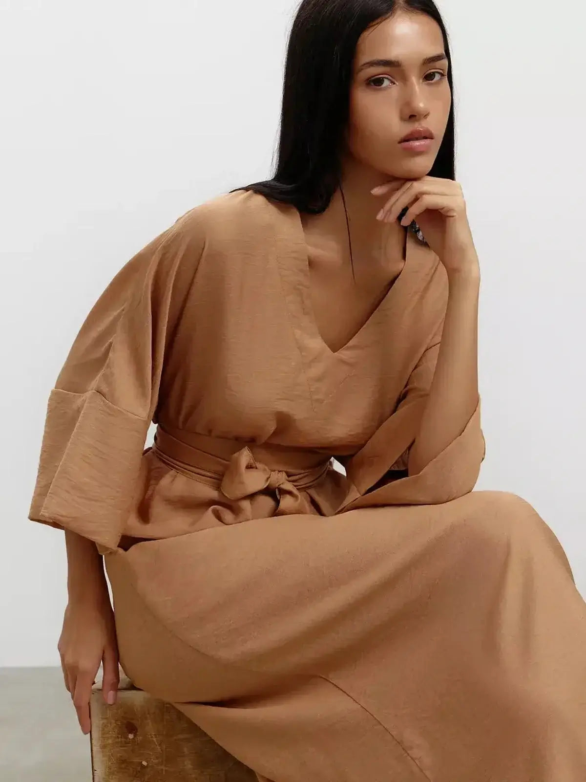 Model wearing the Maxi Dress Dune Whisper, featuring a V-neckline and kimono sleeves in a sandstone hue.