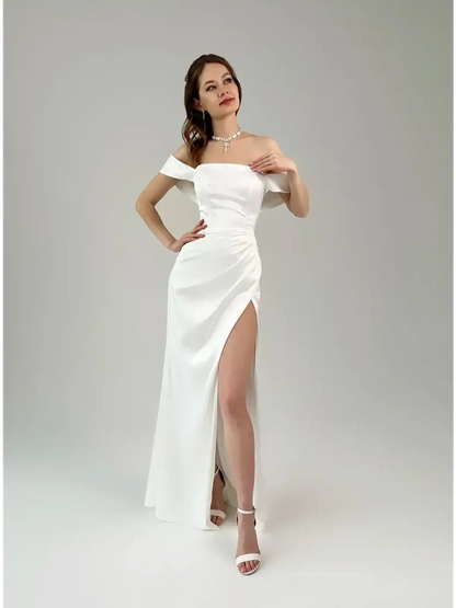 Model in a white satin maxi dress with off-shoulder neckline and thigh-high slit, exuding elegance and glamour.