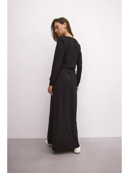 Woman wearing a black maxi dress with a relaxed fit and cinched waist, showcasing urban elegance.