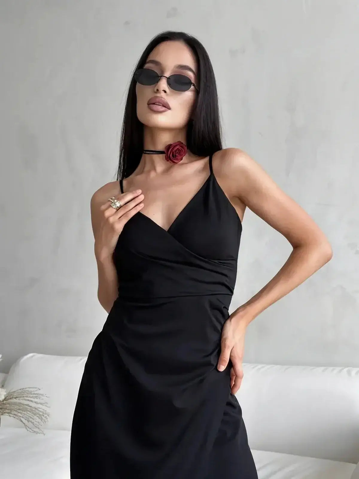 Model wearing the Maxi Dress Éclipse, showcasing a deep V-neckline and stylish accessories in a minimalist setting.