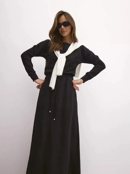 Model showcasing the sleek Maxi Dress Eclipse with a cinched waist and elegant boat neckline, styled for urban fashion.