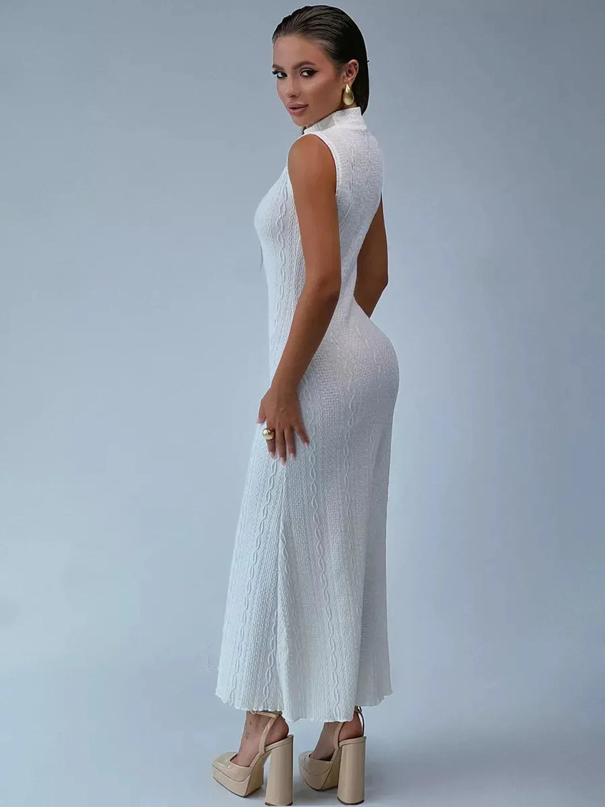 Model wearing the sleeveless Maxi Dress Élan Sculpté in textured jacquard knit, showcasing a sculpted silhouette and high collar.