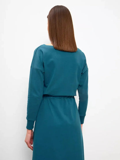Back view of a woman in a stylish forest green maxi dress, showcasing its relaxed fit and elegant silhouette.