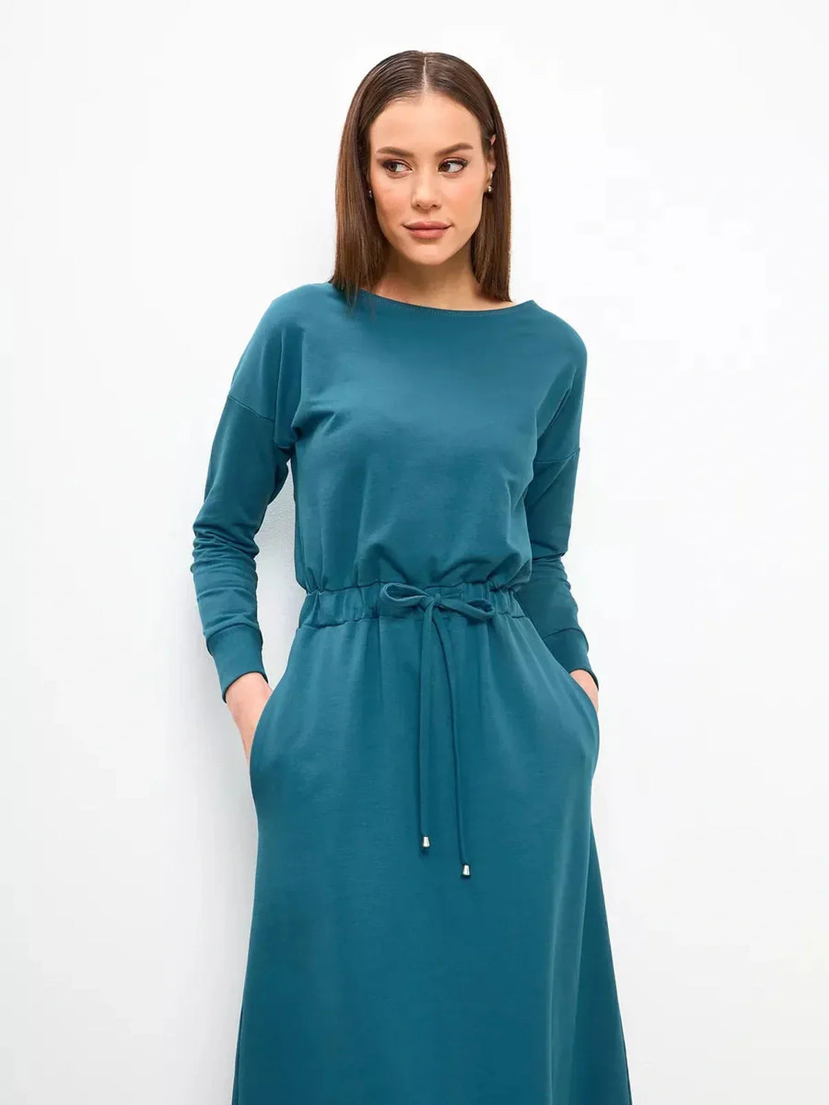 Model wearing a forest green Maxi Dress Evergreen Ease with pockets, featuring a cinched waist and long sleeves.