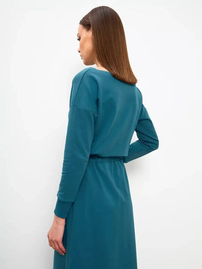 Model showcasing the back view of the Maxi Dress Evergreen Ease in a rich forest green, emphasizing its elegant design.