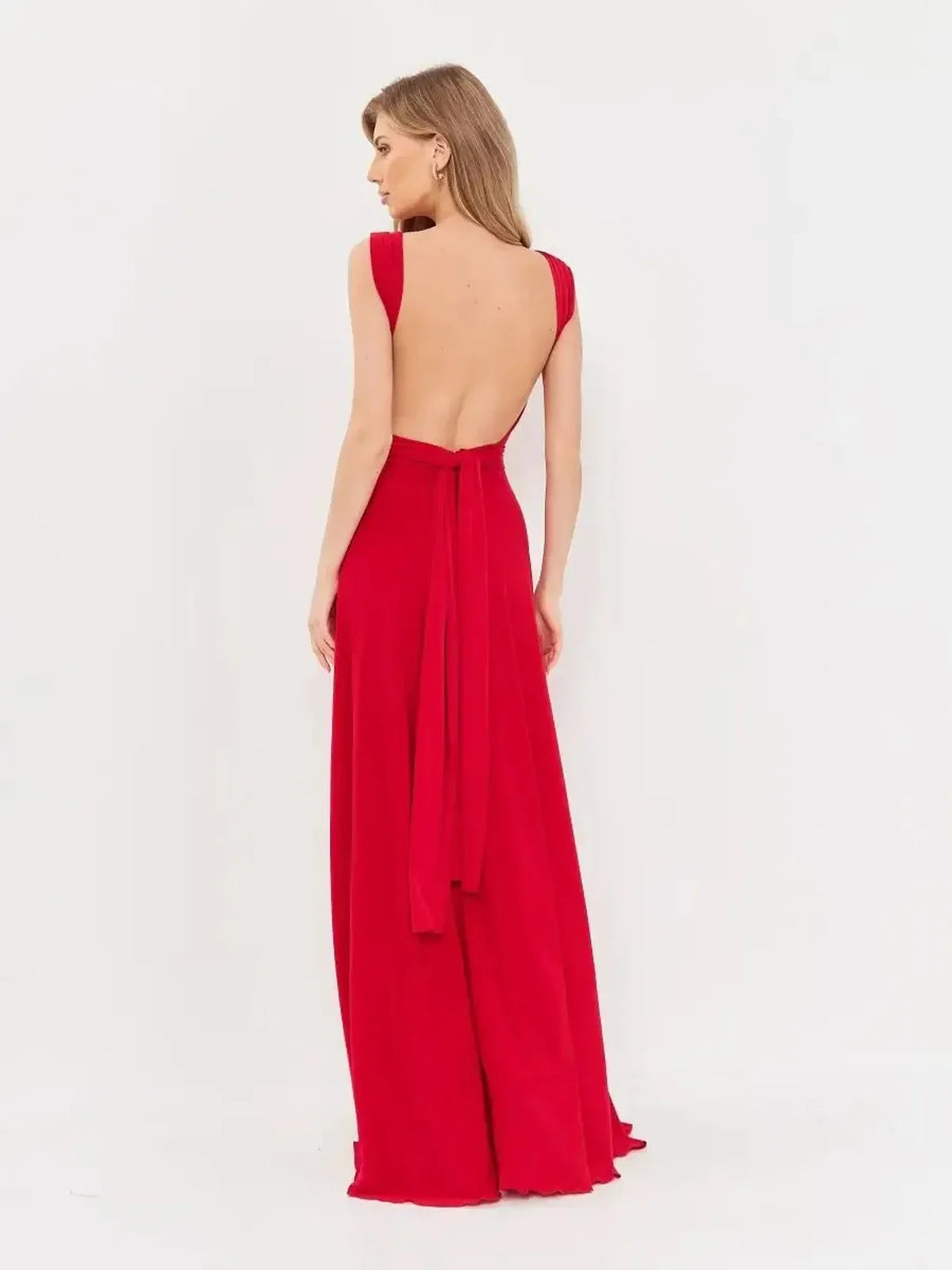 Back view of a model wearing the Maxi Dress Flame Muse, showcasing its open back and flowing red fabric.