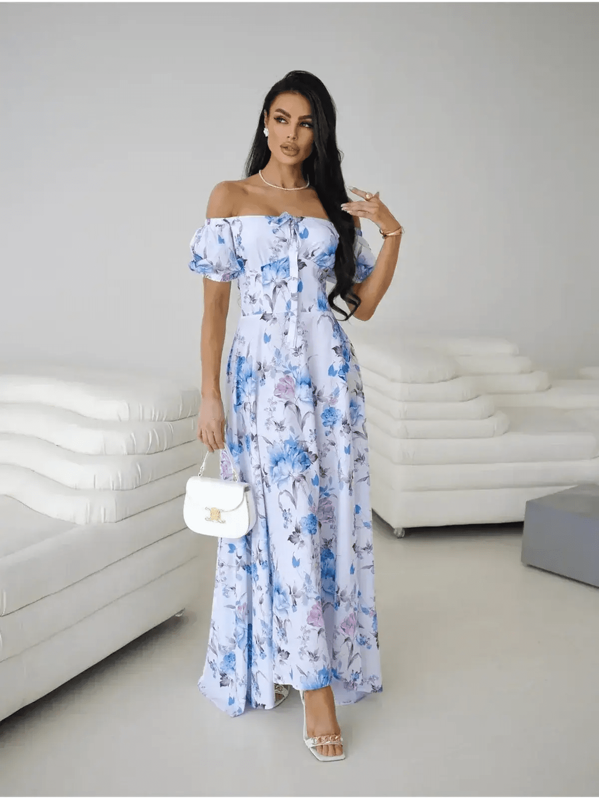 Model wearing an off-shoulder white and blue floral maxi dress with puff sleeves and thigh-high slit.