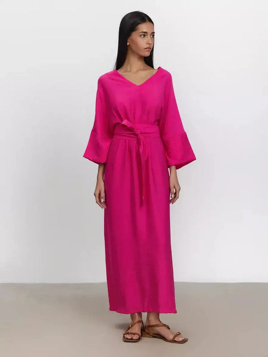 Model wearing a vibrant fuchsia maxi dress with kimono sleeves and a removable belt for a relaxed fit.