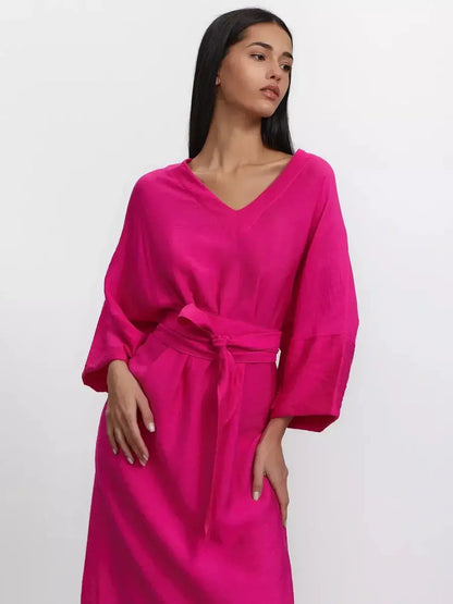 Model in a vibrant fuchsia maxi dress with deep V-neckline and kimono sleeves, showcasing effortless elegance.