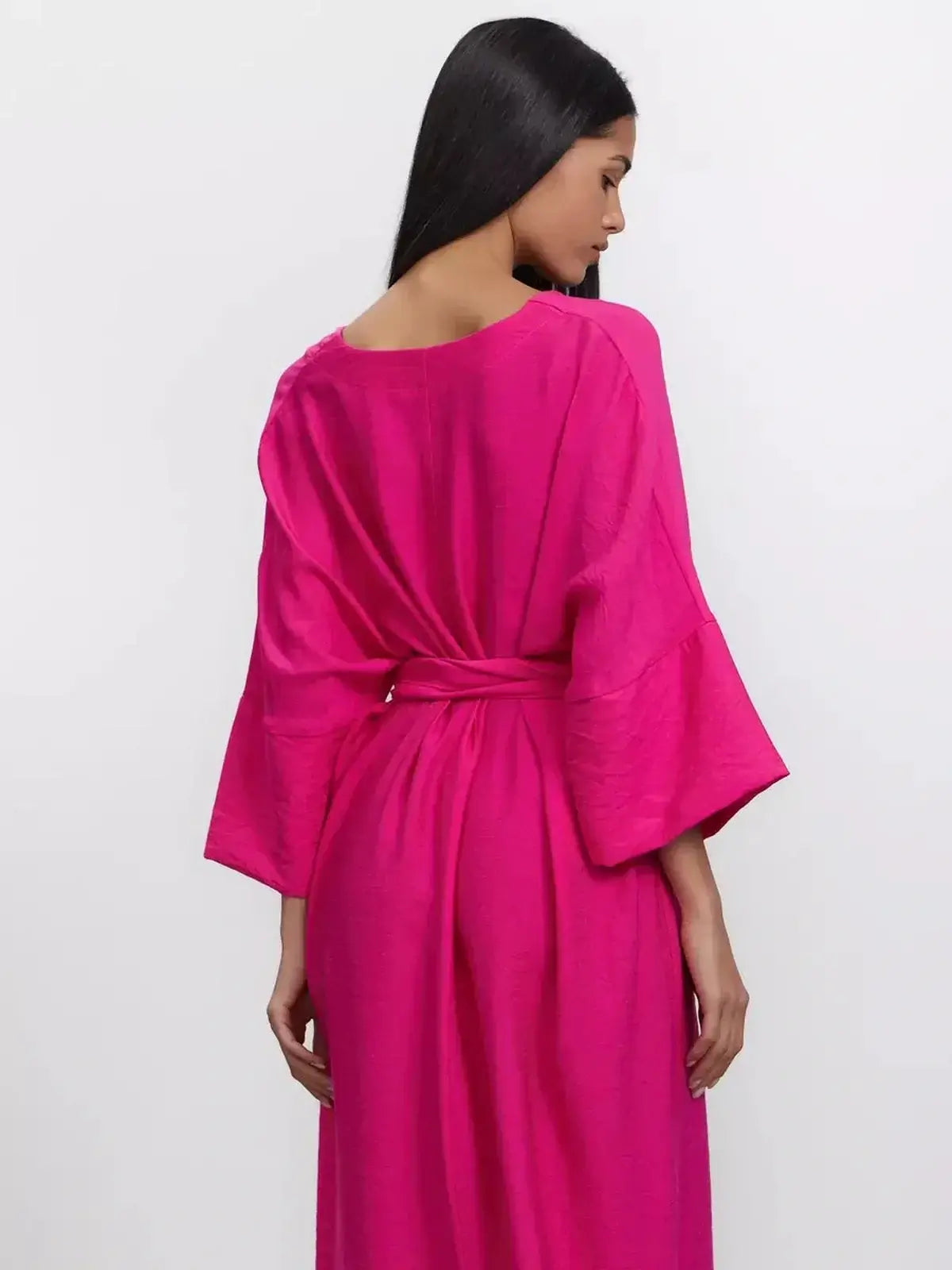 Back view of a model wearing the vibrant fuchsia Maxi Dress Lush Aura, featuring a relaxed fit and kimono-style sleeves.