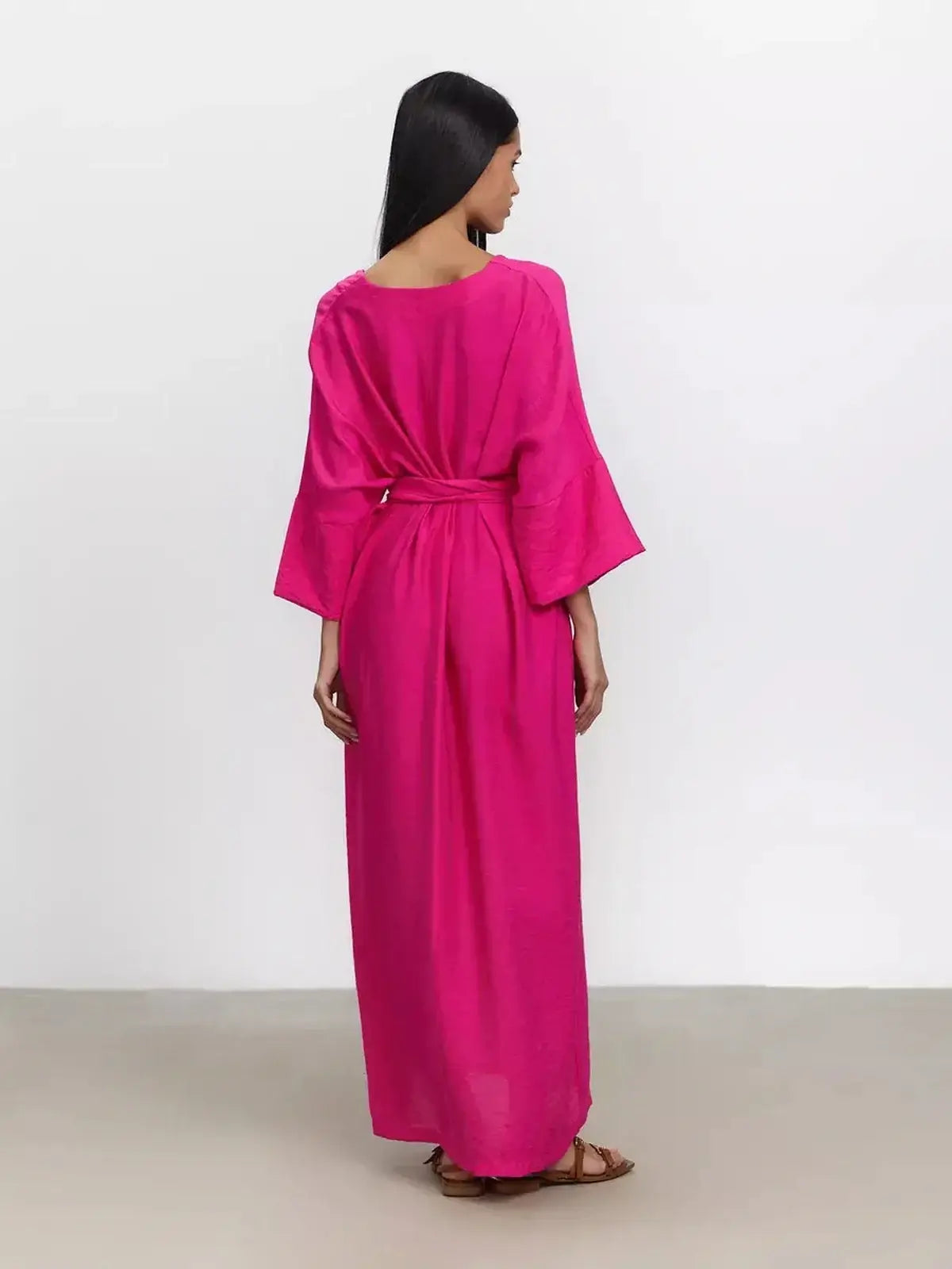 Back view of a woman wearing a vibrant fuchsia maxi dress with kimono sleeves and a removable belt.