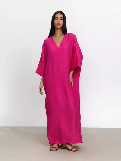 Woman wearing a vibrant fuchsia maxi dress with kimono sleeves and a deep V-neckline, showcasing effortless elegance.