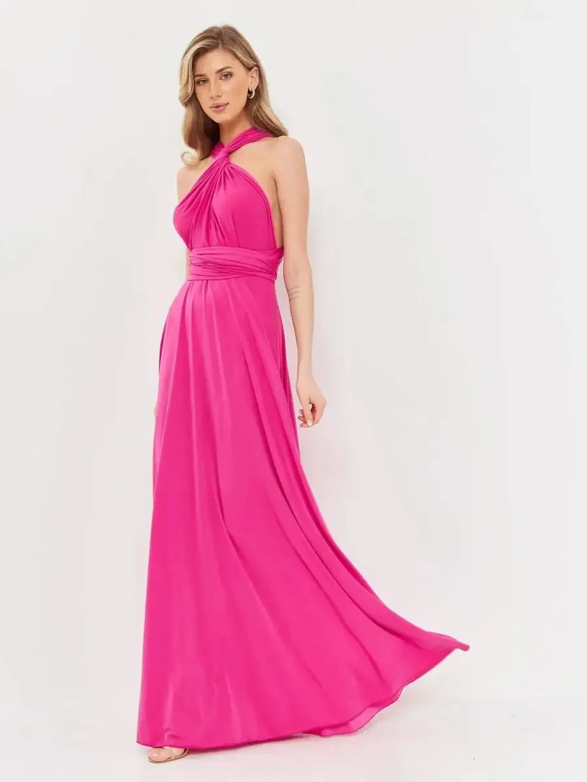 Model wearing the Maxi Dress Lush Twist in vibrant fuchsia pink, showcasing its elegant drape and halter neckline.