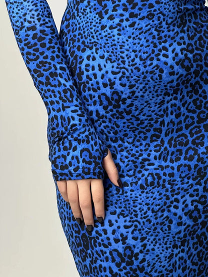 Close-up of a hand in a sleek blue leopard print maxi dress with long sleeves, showcasing bold patterns and elegant design.