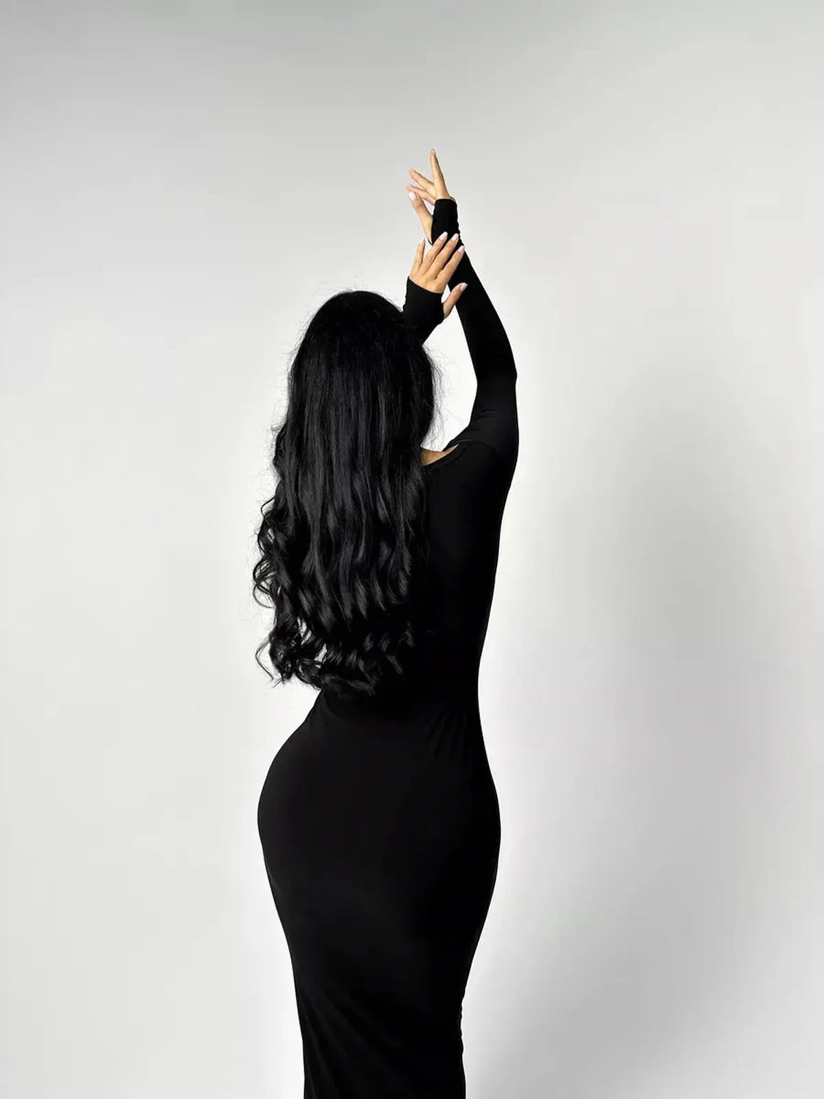Elegant woman in a black long sleeve bodycon maxi dress showcasing a sleek silhouette and modern style.