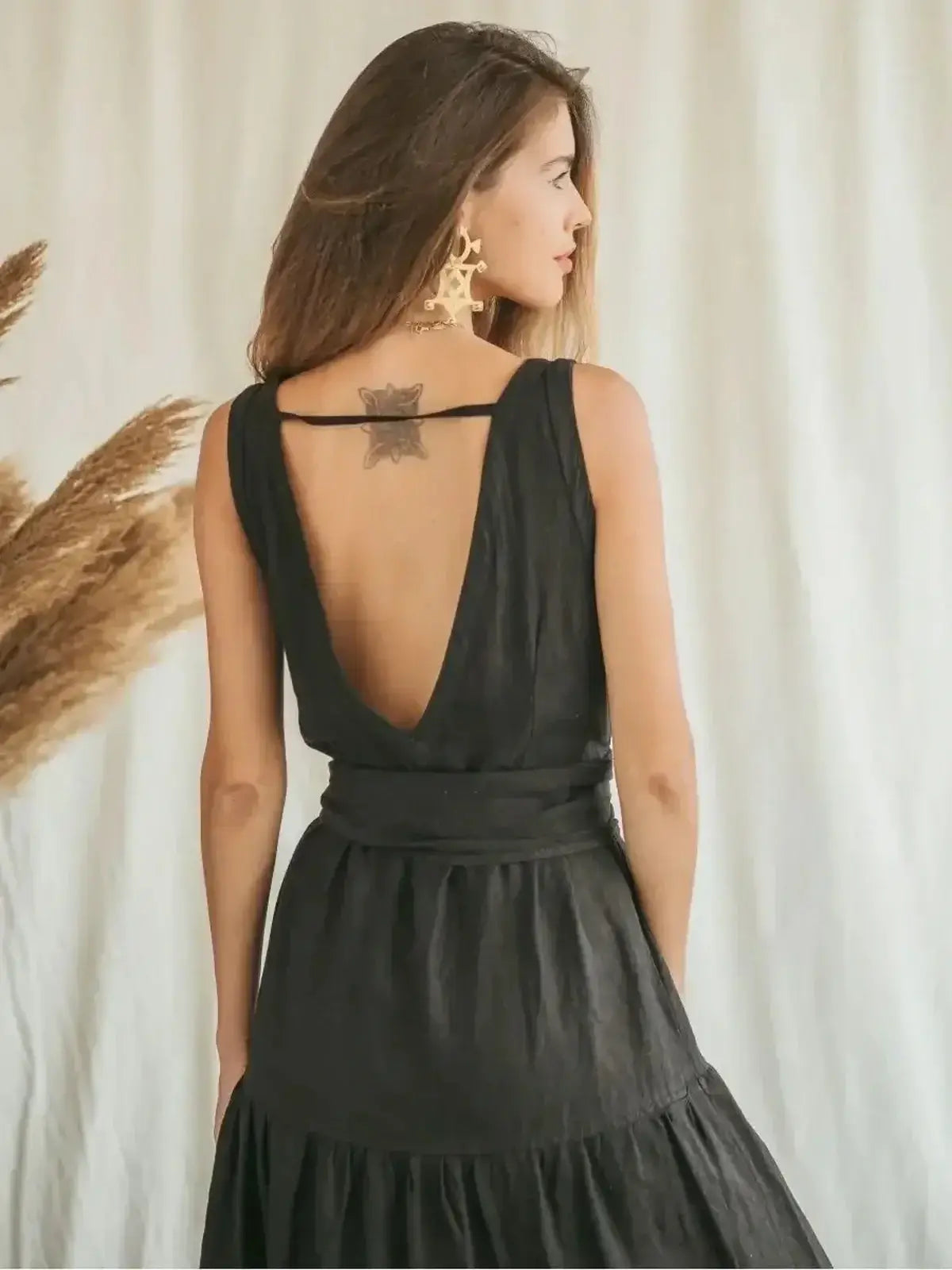 Back view of a model in a black maxi dress showcasing its deep V-neck and A-line silhouette.
