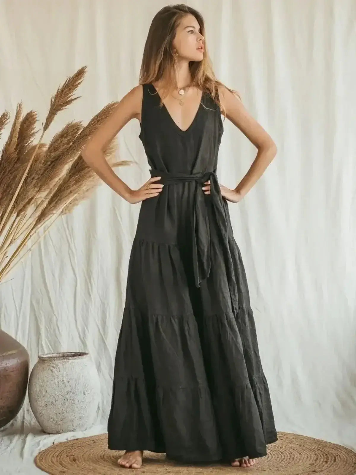 Elegant black maxi dress with deep V-neck, A-line silhouette, and tiered skirt, perfect for summer events.