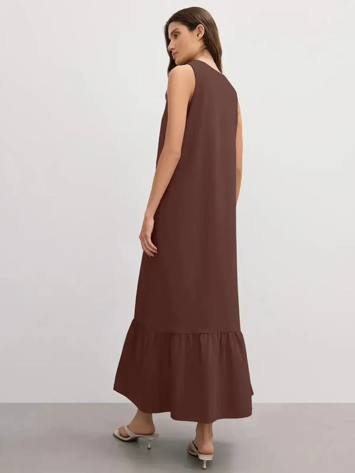 Back view of a model wearing the chocolate-hued Maxi Dress Reverie with a ruffle hem.