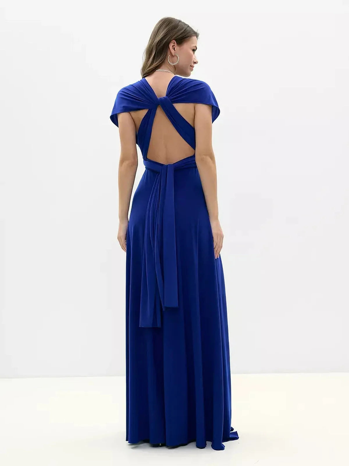 Back view of a woman in a vibrant blue Maxi Dress Sapphire Twist, showcasing an intricate twisted open back design.