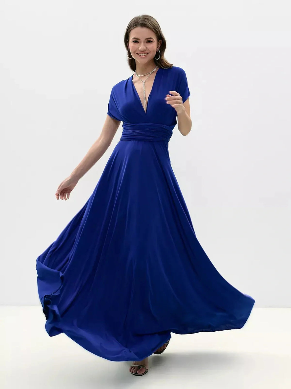 Model wearing a vibrant blue Maxi Dress Sapphire Twist, showcasing its elegant flowing silhouette and twisted back design.