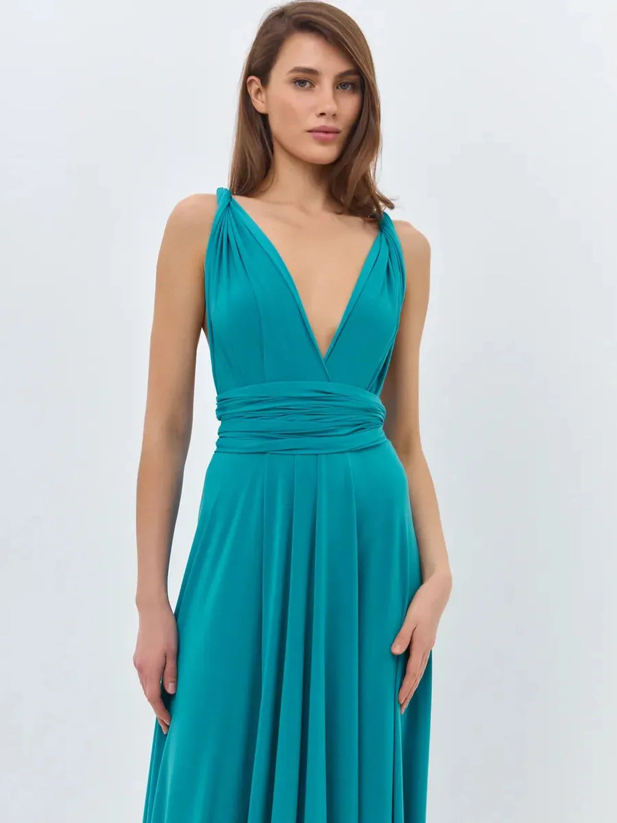 Model wearing a teal maxi dress with a V-neckline and tie straps, showcasing a flowing silhouette.