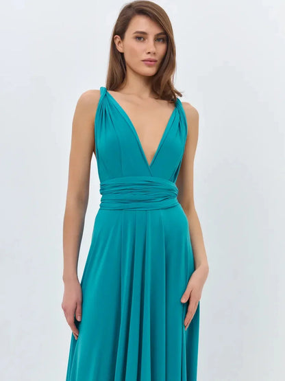 Model wearing a teal maxi dress with a V-neckline and tie straps, showcasing a flowing silhouette.