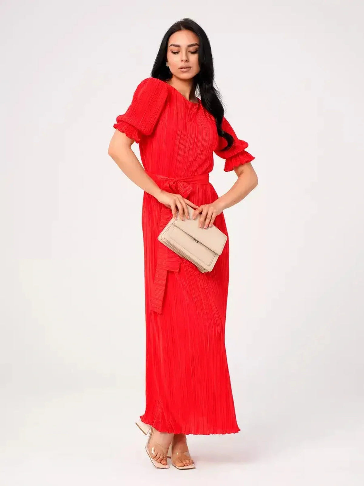 Model wearing a red pleated Maxi Dress Solaria with puff sleeves and a matching belt, perfect for summer events.