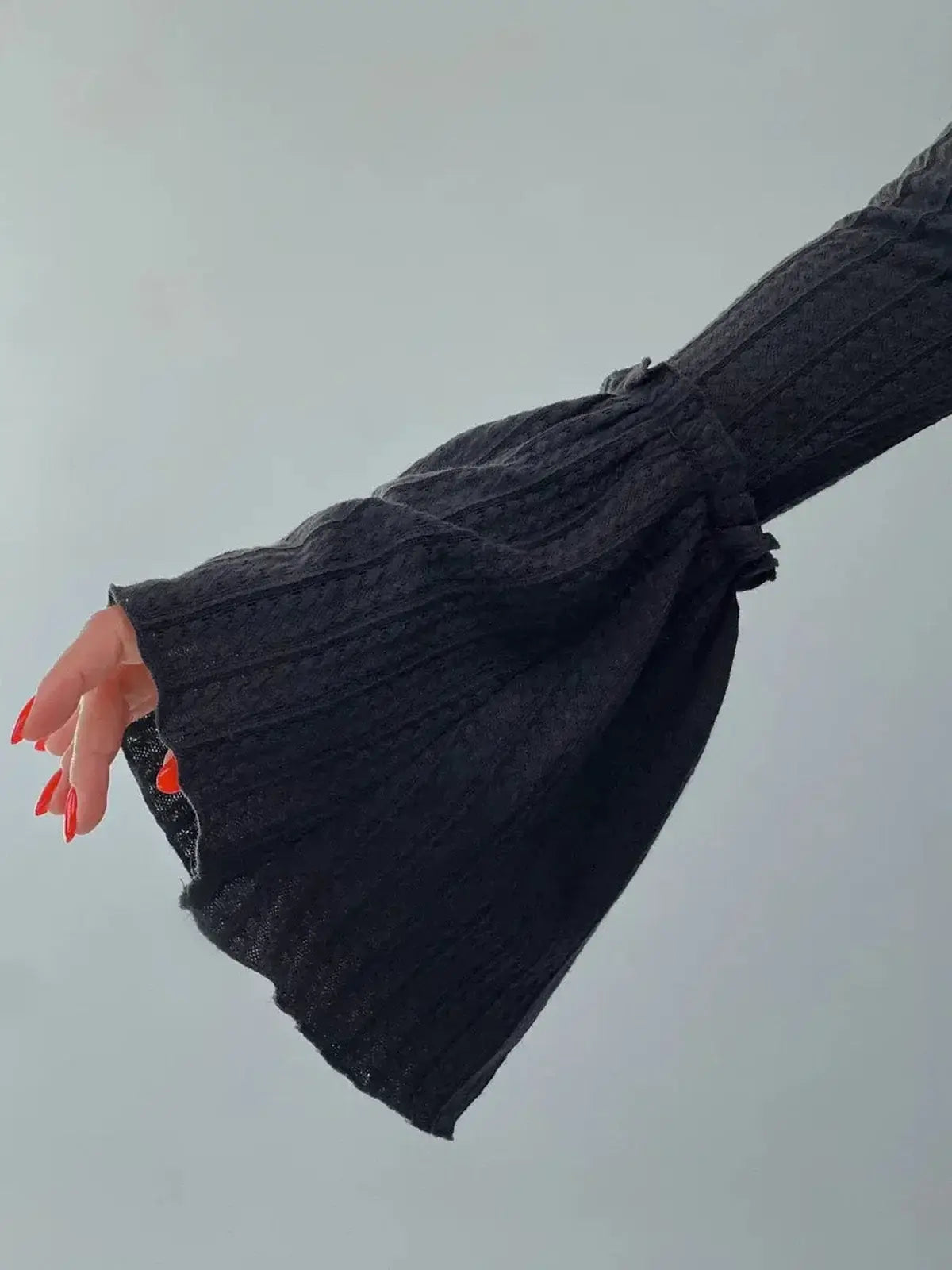 Close-up of the dramatic flared cuff of the Meridian Maxi Dress in ribbed black fabric, showcasing sculptural elegance.