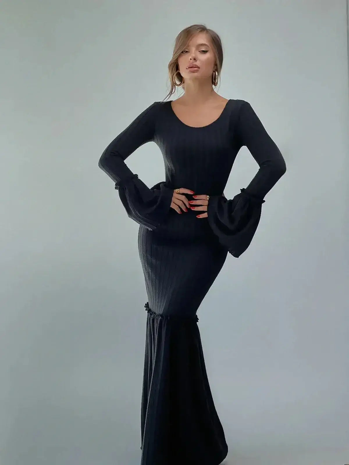 Model wearing the Meridian Maxi Dress, showcasing its sculpted fit and dramatic flared cuffs in a sleek black design.