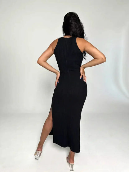 Back view of a woman in a black ribbed Midi dress featuring a side slit and cross-strap neckline.