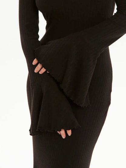 Close-up of the elegant bell sleeves of a black midi dress, showcasing a ribbed knit texture.
