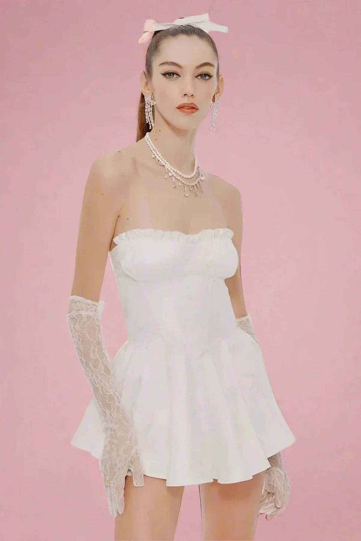 Model wearing a stylish white mini dress with lace gloves and accessories, set against a pink background.