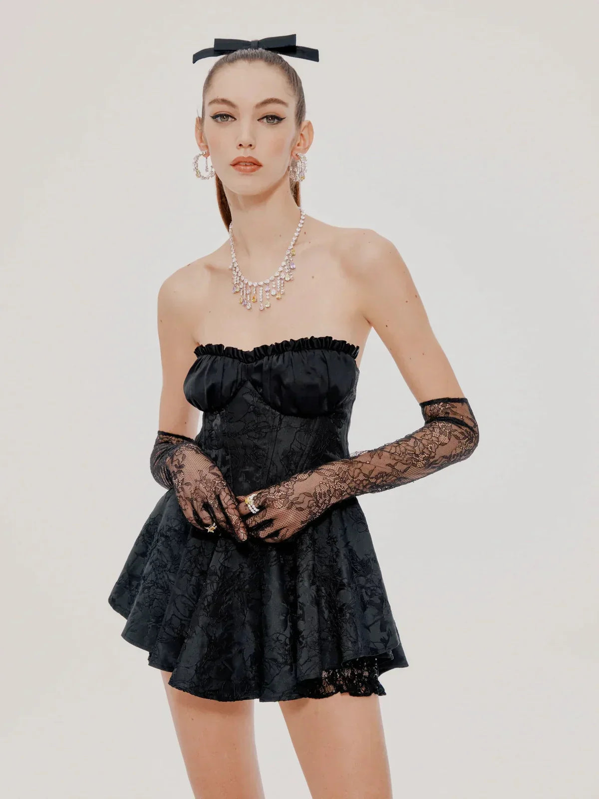 Elegant black mini dress with lace detailing, featuring a structured bodice and stylish accessories for a chic evening look.