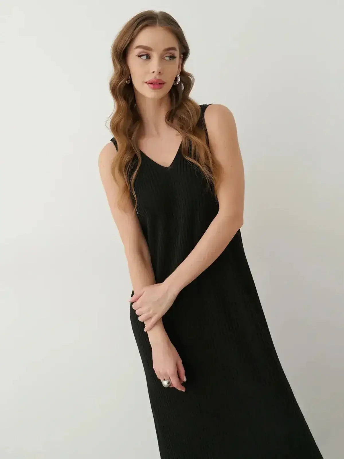 Model in the Muse Knit Maxi Dress, a sleek black sleeveless dress with V-neckline and subtle side slit.