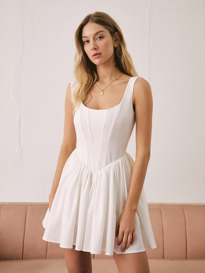 Model wearing the Nell Mini Dress, a white linen dress featuring a sculpted bodice and flared skirt, perfect for summer occasions.